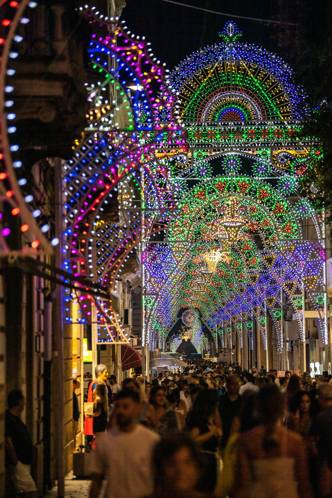 Traditional luminarie arches lighting a crowded street in Salento, Southern Italy