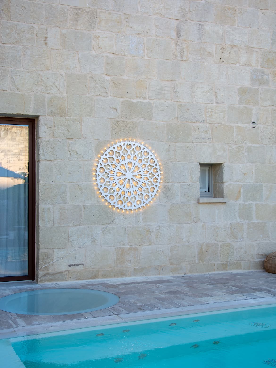 Rosone Bordeaux mounted on a Lecce stone wall beside a pool